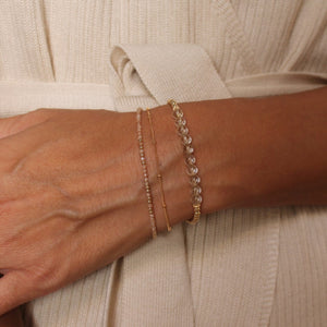 Model wearing rutilated quartz beaded bracelet with satellite chain and morse code bracelets