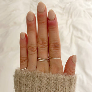 model wearing silver beaded stacking ring, twisted stacking ring, silver band and the square beaded stacking ring